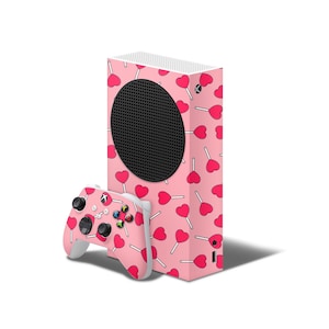 May include: A pink and white Xbox Series X console with a pink and white controller. The console has a design of pink hearts and lollipops.