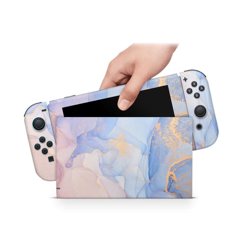 May include: A Nintendo Switch console with a custom skin featuring a blue, pink, and gold abstract marble design. The console is closed and the Joy-Con controllers are attached.
