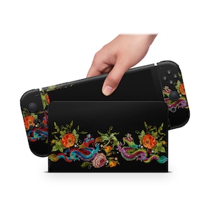 May include: A black Nintendo Switch console case with a floral and dragon design. The case features a black background with colorful flowers, vines, and two dragons.