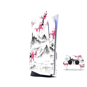 May include: A white gaming console and matching wireless controller featuring a black and white ink wash landscape illustration of mountains and a pagoda, accented with vibrant pink cherry blossom branches across the surface of both items.