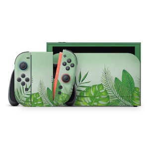 Può includere: Una console Nintendo Switch e controller con un design a foglie tropicali. I controller sono verde chiaro con pulsanti neri e un lato color corallo. La console è verde chiaro con un motivo a foglie abbinato.