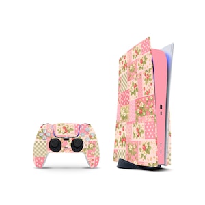 May include: A PlayStation 5 console and controller set featuring a patchwork design with strawberries and floral patterns in pink, white, and green. The console has a pink side panel and a black base. The controller has black buttons.