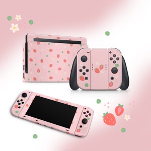 Pode incluir: Console Nintendo Switch rosa e controladores Joy-Con com um padrão de morangos e flores. O console tem uma tela preta e os Joy-Cons têm botões pretos.