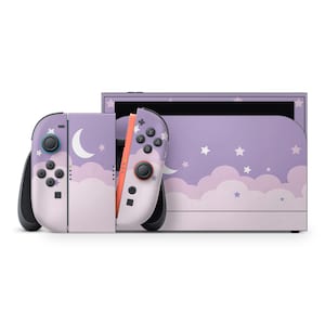 May include: A Nintendo Switch console and Joy-Con controllers with a custom skin featuring a purple sky design with white clouds, stars, and a crescent moon. The controllers have black buttons and joysticks, with a pink accent.