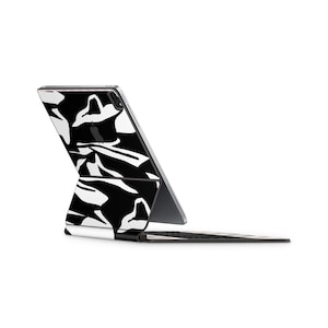 Pode incluir: Um iPad com um padrão preto e branco com uma capa de teclado preta. O iPad está dobrado para trás para mostrar o teclado.