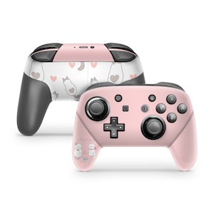 May include: Pink Nintendo Switch controller with a white and pink cat design. The controller has a white background with pink hearts and cats. The text "love" is written on the controller.