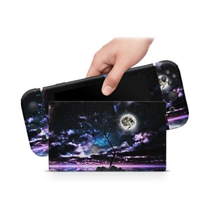Puede incluir: Una piel negra para la consola Nintendo Switch con un cielo oscuro, nubes, una luna llena y la silueta de un árbol solitario. La piel está diseñada para la consola Nintendo Switch y los Joy-Cons.