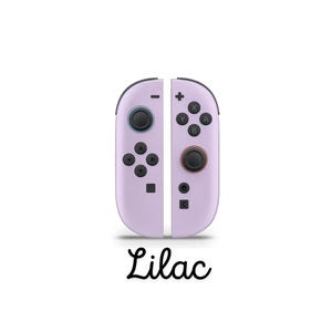 May include: Lilac-coloured game controllers with black buttons and directional pads. The controllers are split into two vertical halves, each with a set of buttons and a joystick. The word "Lilac" is written in cursive below the controllers.