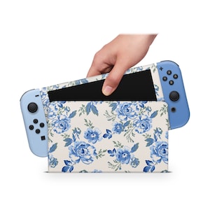 May include: A blue Nintendo Switch console with a floral design case. The case has a white background with blue flowers and green leaves.