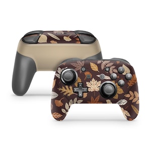 Könnte beinhalten: Ein brauner Nintendo Switch-Controller mit einem Herbstlaubmuster. Der Controller hat einen braunen Hintergrund mit gelben, orangefarbenen und roten Blättern.