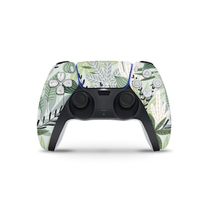 May include: A wireless game controller with a botanical leaf pattern in shades of green, white, and gray. The controller has black handles and buttons, with a blue accent. The design features various leaf shapes and textures.