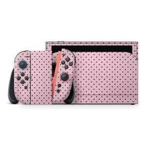 May include: A pink Nintendo Switch console and controllers with a black polka dot pattern. The controllers are detached, showing the orange rail. The console is in the dock, and the design covers the entire system.