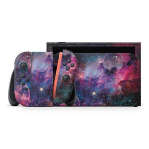 以下が含まれることがあります： 鮮やかな銀河のデザインが施されたNintendo SwitchのコンソールとJoy-Conコントローラー。コントローラーには黒いボタンとオレンジ色のレールが付いています。ドックとコントローラーは、紫、ピンク、青の色合いの星雲で覆われており、宇宙をテーマにしています。
