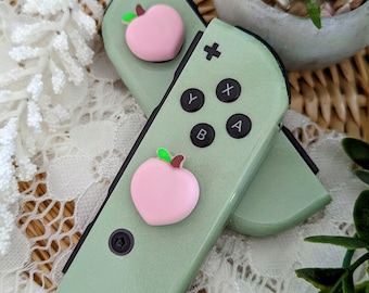 Empuñaduras de pulgar Peach: Tapas de silicona para joysticks de Switch/Lite/OLED (2 unidades)