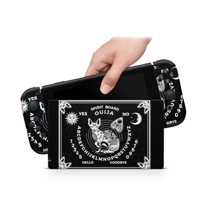 May include: A black and white Nintendo Switch console skin featuring a Ouija board design with a cat and the words "Spirit Board Ouija" and "Yes" and "No" on the board.