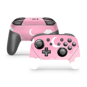 Op de afbeelding: Een roze Nintendo Switch-controller met een wit en roze maan- en wolkenontwerp.