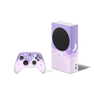 May include: A purple and white Xbox Series X console and controller with a moon and stars design. The console has a black speaker grille and the controller has a white faceplate.