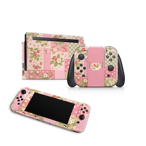 Op de afbeelding: Een set Nintendo Switch-accessoires met een patchwork-ontwerp met aardbeien en bloemenpatronen. De set bevat een console, twee Joy-Con-controllers en een handheld-apparaat, allemaal in roze, groen en wit.