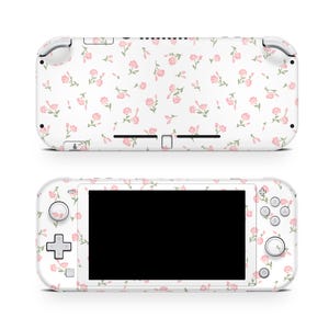 Könnte beinhalten: Weiße Nintendo Switch Lite Konsole mit einem rosa Blumenmuster. Die Konsole hat einen schwarzen Bildschirm und weiße Knöpfe.