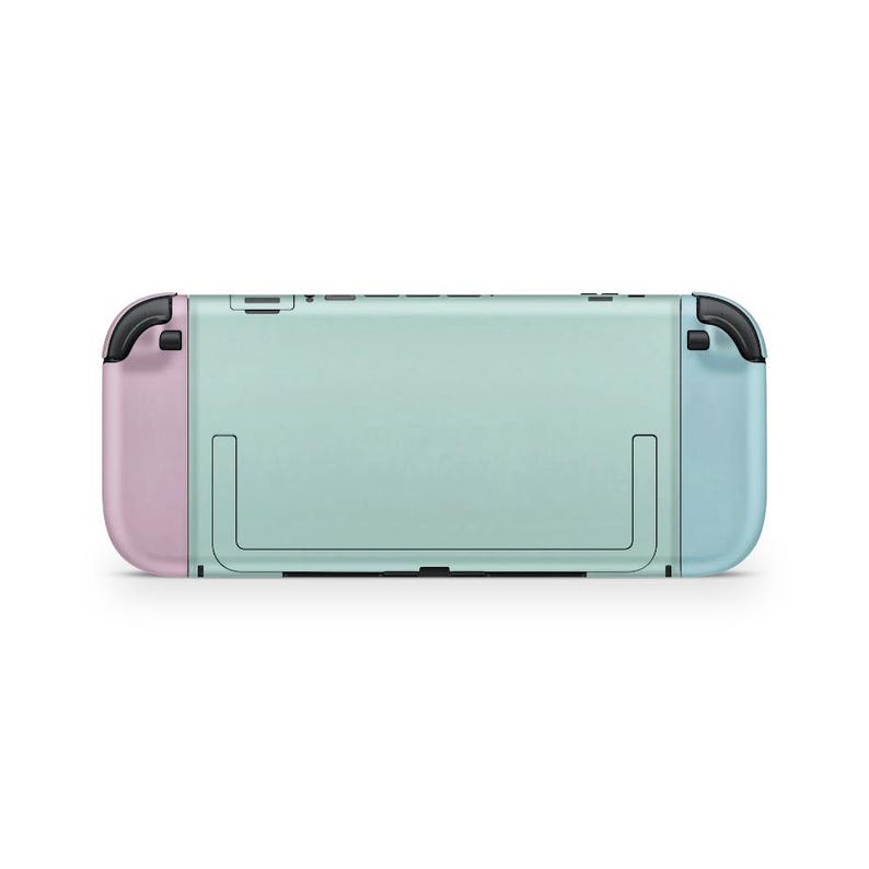 May include: A mint green and pastel colour gaming console. The console has a light blue right controller and a pink left controller. The back of the console is mint green with a black kickstand and black buttons on top.
