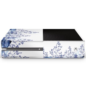 May include: White gaming console with a blue and white floral design. The console has a black top and a blue and white floral design on the front and sides.