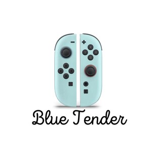 May include: Two pale blue game controllers with black buttons and joysticks. The controllers are positioned side by side, with the text "Blue Tender" in a cursive font below. The controllers have various buttons and directional pads.
