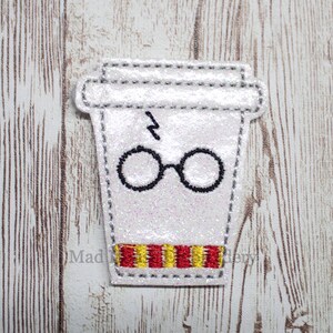May include: White glitter coffee cup with a lightning bolt and glasses on it. The cup has red and yellow stripes around the bottom.
