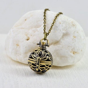 Peut inclure: Un collier doré avec un pendentif rond en forme de médaillon orné. Le médaillon présente un motif détaillé de cercles entrelacés et un petit loquet.