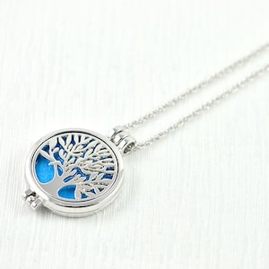 May include: A silver necklace with a round pendant featuring a tree of life design. The pendant has a blue background and the tree is cut out, creating a delicate and intricate design.