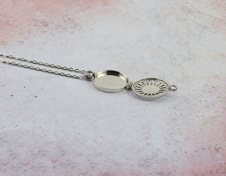 May include: A silver necklace with a round pendant that opens to reveal a decorative design. The pendant is attached to a delicate silver chain.