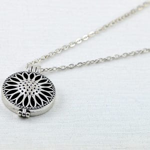 May include: Silver necklace with a round, openwork pendant in the shape of a flower.