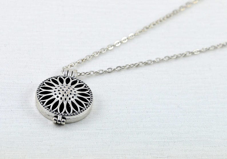 May include: Silver necklace with a round, openwork pendant in the shape of a flower.
