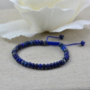 May include: A blue lapis lazuli beaded bracelet with a blue cord closure.