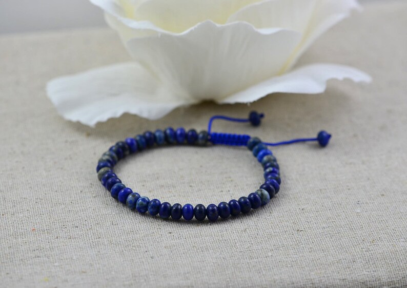May include: A blue lapis lazuli beaded bracelet with a blue cord closure.