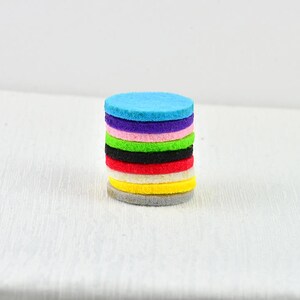 May include: A stack of ten round felt pads in various colors, including blue, purple, pink, green, black, red, white, and yellow.