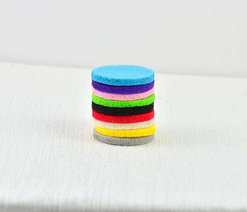 May include: A stack of ten round felt pads in various colors, including blue, purple, pink, green, black, red, white, and yellow.