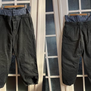 Może przedstawiać: Dwie pary czarnych spodni z cordury z niebieską pikowaną podszewką. Spodnie mają luźny krój i mankiety.