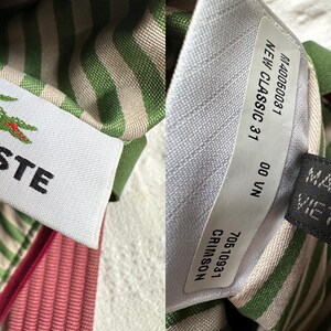 May include: Close-up of a white tag with the Lacoste logo, a green crocodile with red accents, and the brand name in black. The tag is sewn into striped fabric in green and white, with a pink fabric visible.