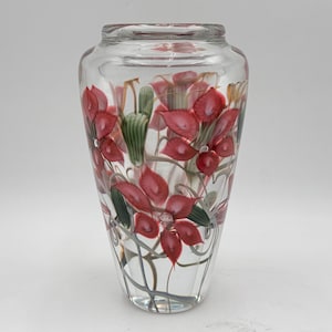 Può includere: Vaso di vetro trasparente con un design floreale. Il vaso presenta fiori rossi con accenti verdi e bianchi. I fiori sono dipinti all'esterno del vaso. È un oggetto decorativo.