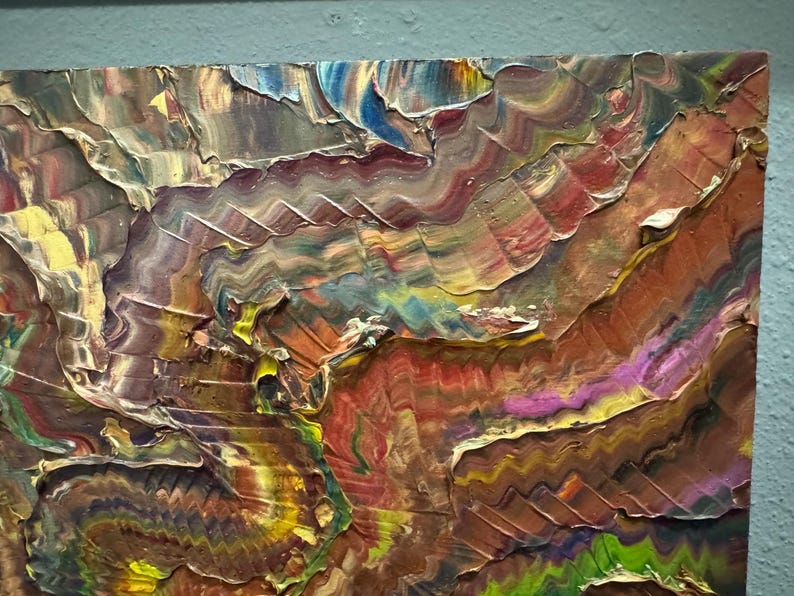 Puede incluir: Pintura abstracta texturizada con gruesas pinceladas en tonos marr&oacute;n, rojo, amarillo, azul y verde. La obra de arte tiene un estilo empaste en capas, creando un efecto tridimensional. La pintura est&aacute; sobre un lienzo cuadrado.