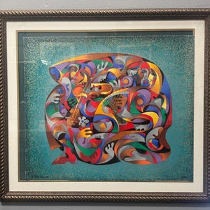 Könnte beinhalten: Ein gerahmtes abstraktes Gemälde mit einer lebendigen, mehrfarbigen Komposition aus ineinandergreifenden Formen und Figuren. Das Kunstwerk zeigt eine zentrale Ansammlung stilisierter Formen in Rot-, Blau-, Gelb- und Violetttönen vor einem texturierten blaugrünen Hintergrund.