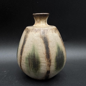 May include: A ceramic vase with a bulbous body and a narrow neck. The vase features vertical brushstrokes in shades of brown, green, and black against a beige background. The vase is approximately 8 inches tall.