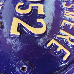 May include: A purple oval-shaped house number sign with gold lettering. The number 2505 is visible on the sign.