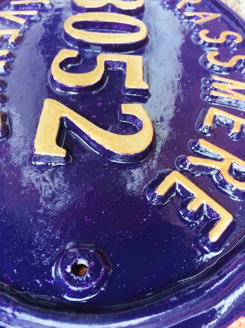 May include: A purple oval-shaped house number sign with gold lettering. The number 2505 is visible on the sign.