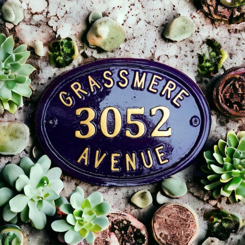 May include: A purple and gold oval-shaped house number sign with the text "Grassmere 3052 Avenue".