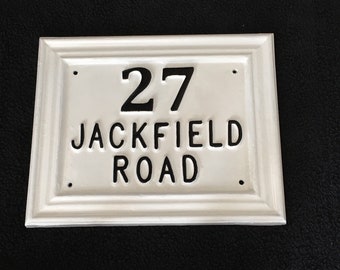 Puede incluir: Placa de número de casa rectangular blanca con letras negras. El número 27 se muestra sobre las palabras "Jackfield Road".