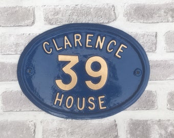 May include: A blue oval-shaped house number plaque with gold lettering. The plaque reads "Clarence 39 House".