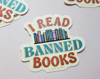 May include: A sticker with a bookshelf full of colorful books and the text "I read banned books" in a retro font. The sticker is cream colored with blue, red, and orange accents. The text "Classic Murphy" is at the bottom of the sticker.