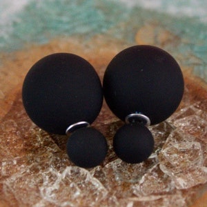 May include: A pair of black double-sided stud earrings. Each earring features two black spheres.