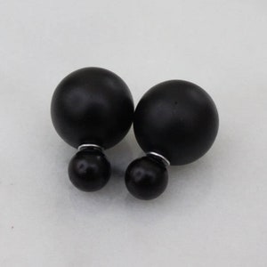 May include: A pair of black double-sided stud earrings. Each earring features a large black sphere with a smaller black sphere on the back.